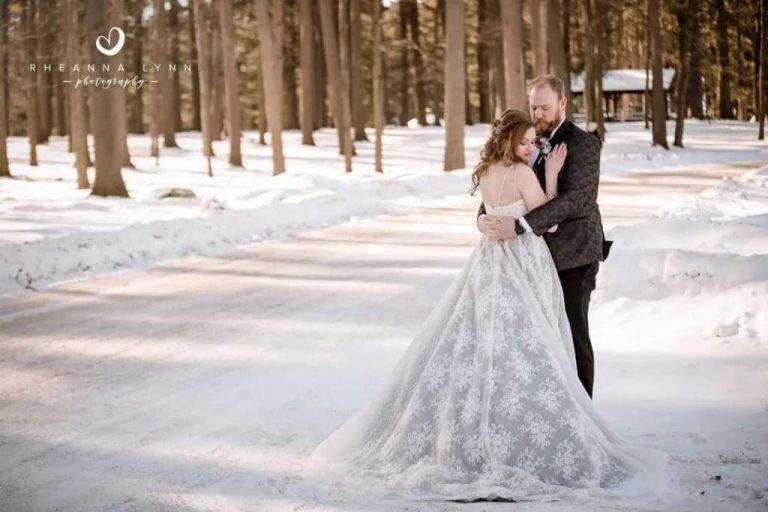 Newly married couple standing in snow.